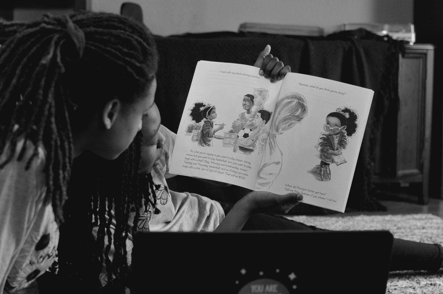 Dos personas leyendo un libro infantil juntas en interiores.